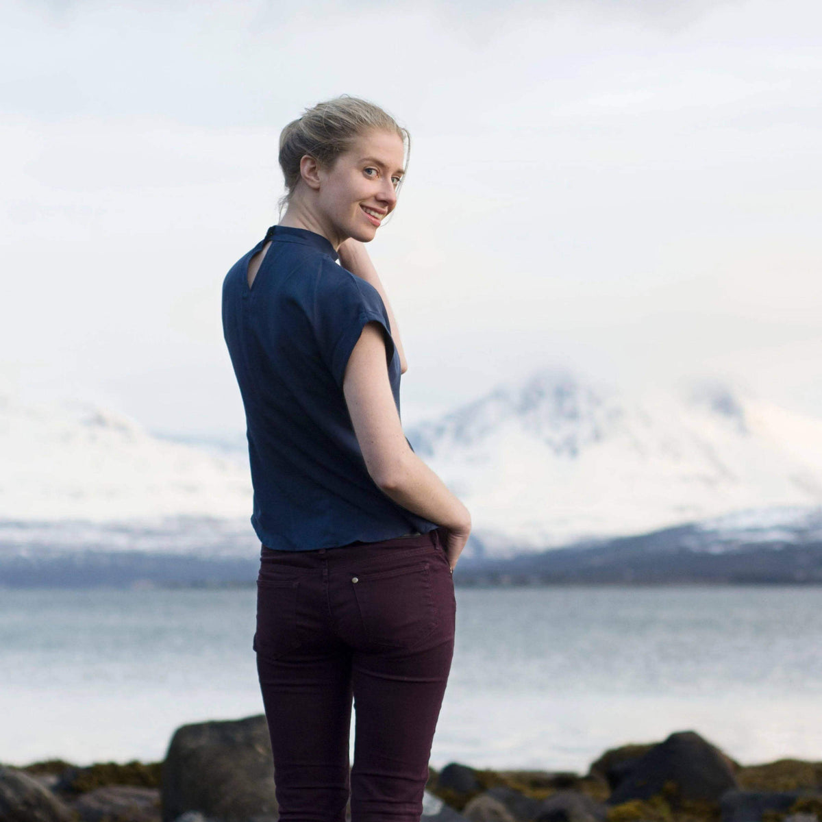 Model wearing Tulip Top Paper Pattern by a scenic lake with mountains in the background.