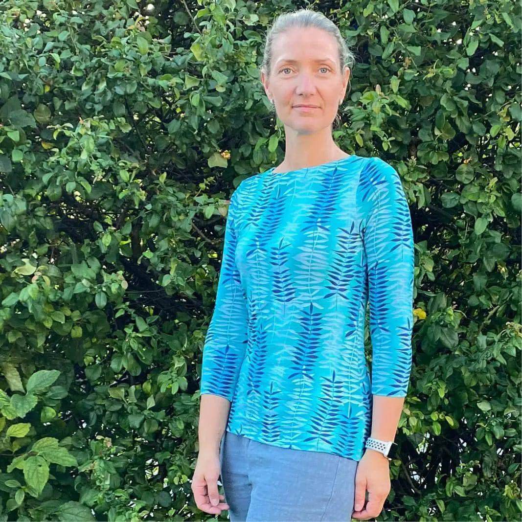 Model wearing a blue patterned T-shirt made using T-shirt Paper Pattern, set against a green bush background.