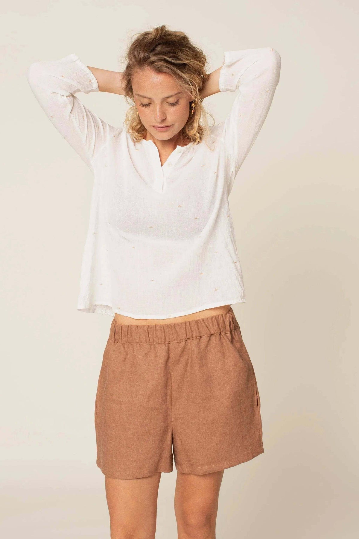 Woman wearing a white Whisper blouse Paper Pattern with brown shorts, demonstrating a casual summer look.