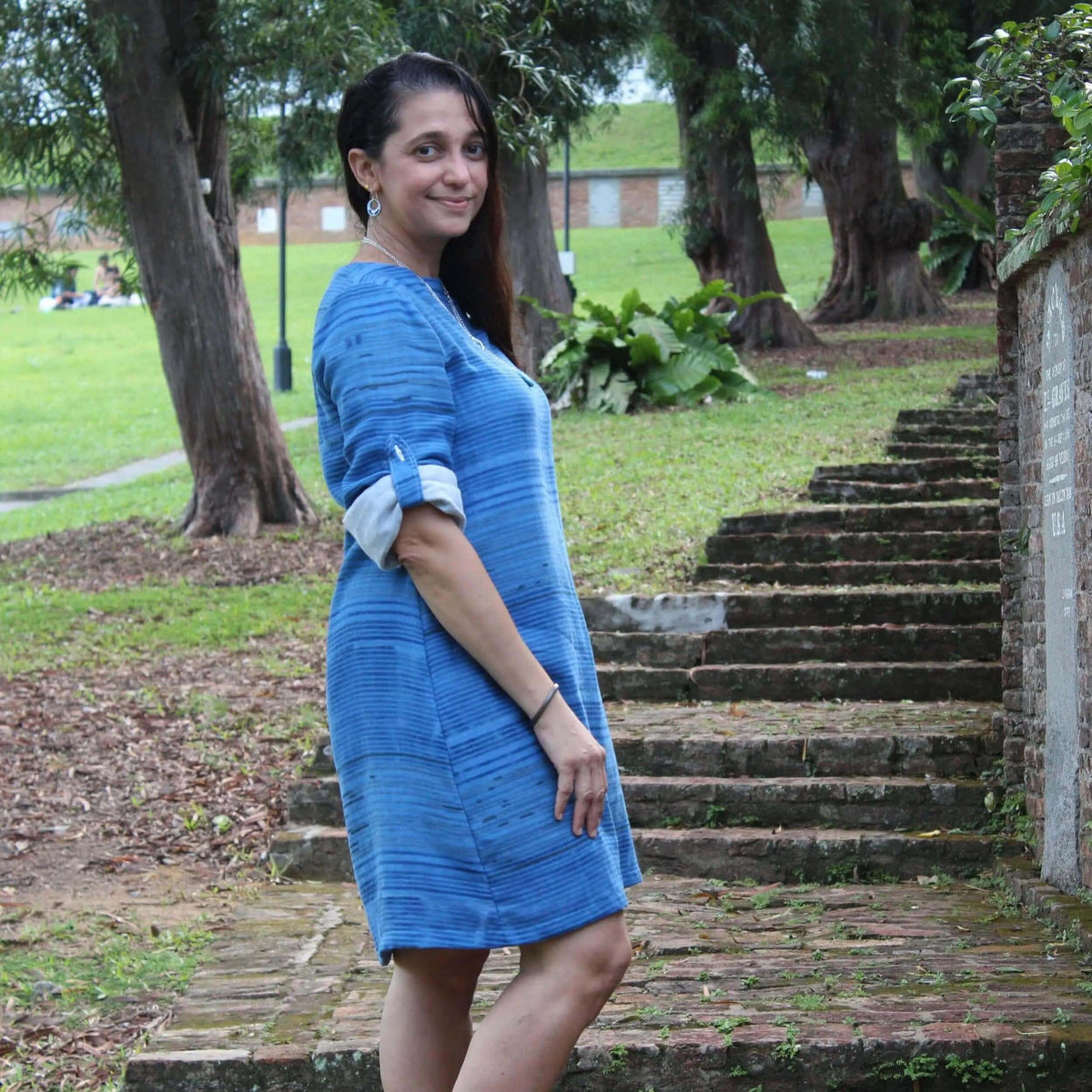 Model wearing a blue dress made from Whisper blouse Paper Pattern fabric, surrounded by greenery.