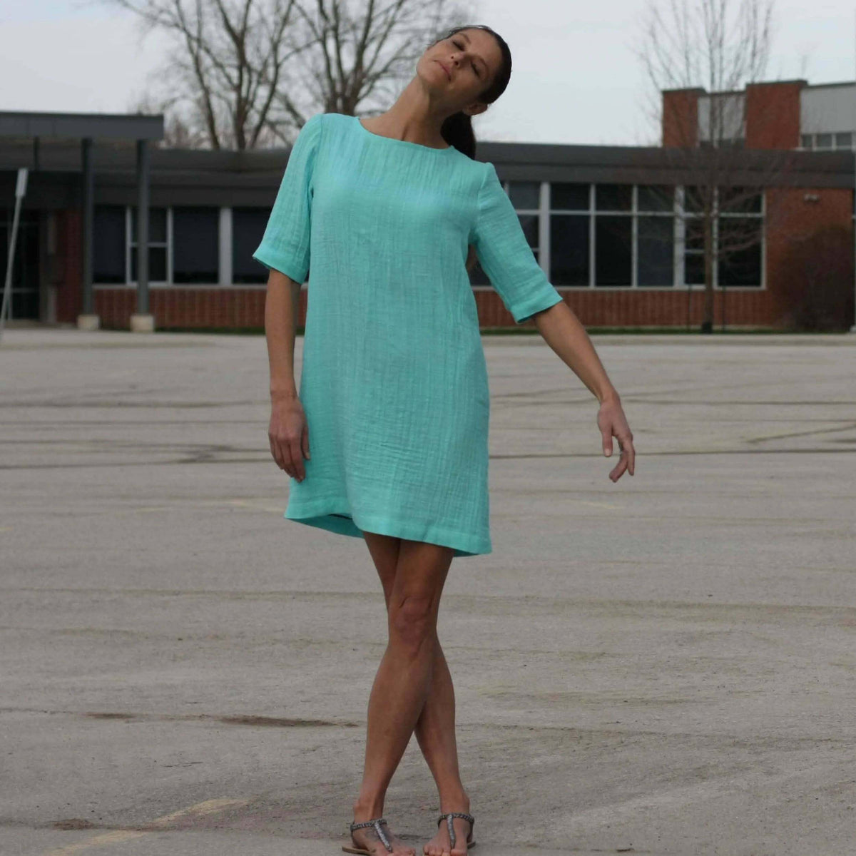 Whisper blouse Paper Pattern model wearing a lightweight, breathable turquoise dress in an outdoor setting.