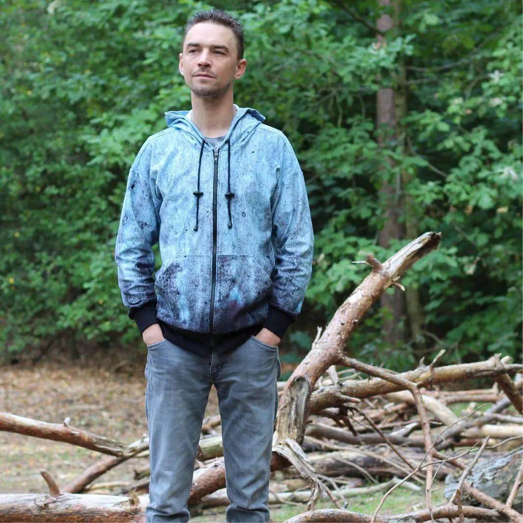 Man wearing a Zipper hoodie paper pattern standing in a forest, surrounded by fallen tree branches.