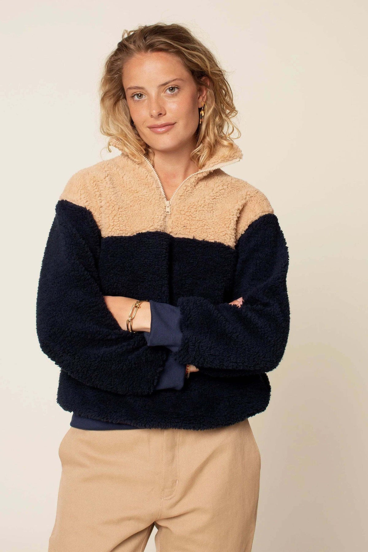 Model wearing a cozy Zip Up Sweater paper pattern in navy and beige, showcasing a zip-up front and high collar.