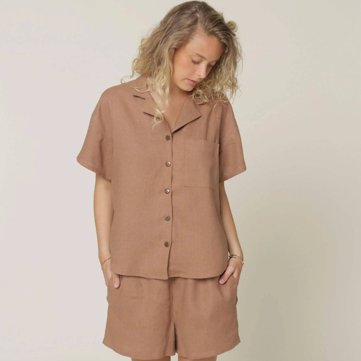 A model wearing the Camp Shirt and shorts Paper Pattern in a stylish brown fabric.