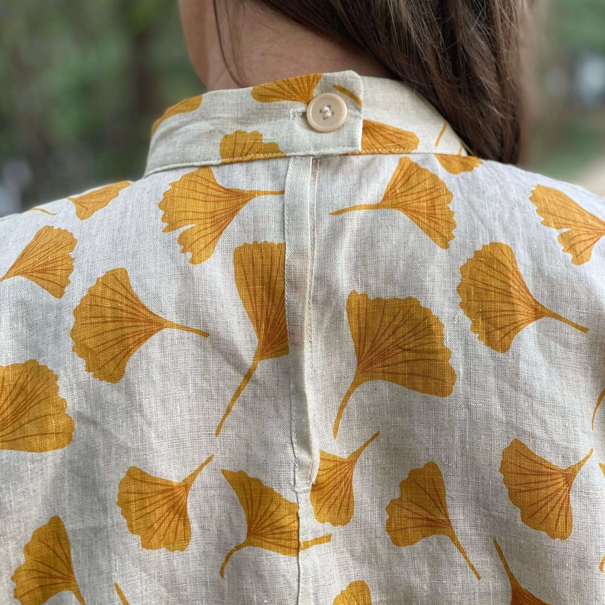 Back view of a person wearing the Tulip Top Paper Pattern with a button closure and ginkgo leaf print.