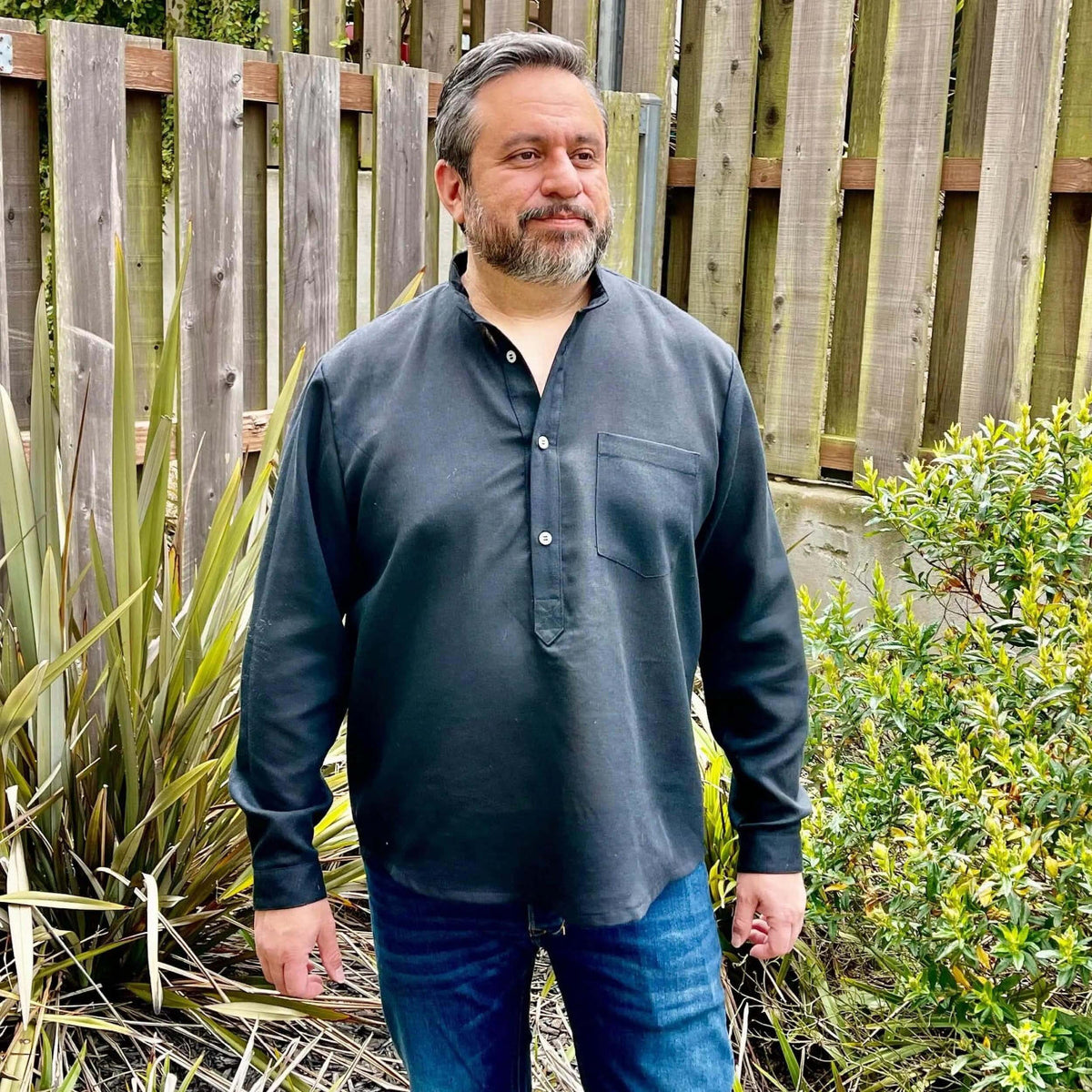 Man wearing Men's Tunic paper pattern with banded collar and button placket in a garden setting.